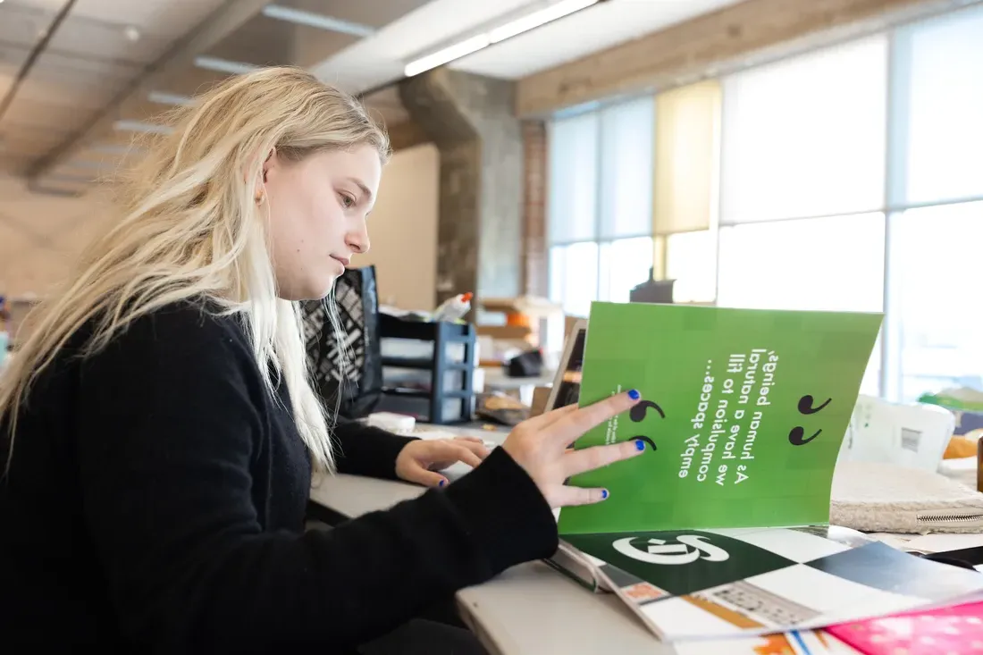 A person reading an art book in a classroom.